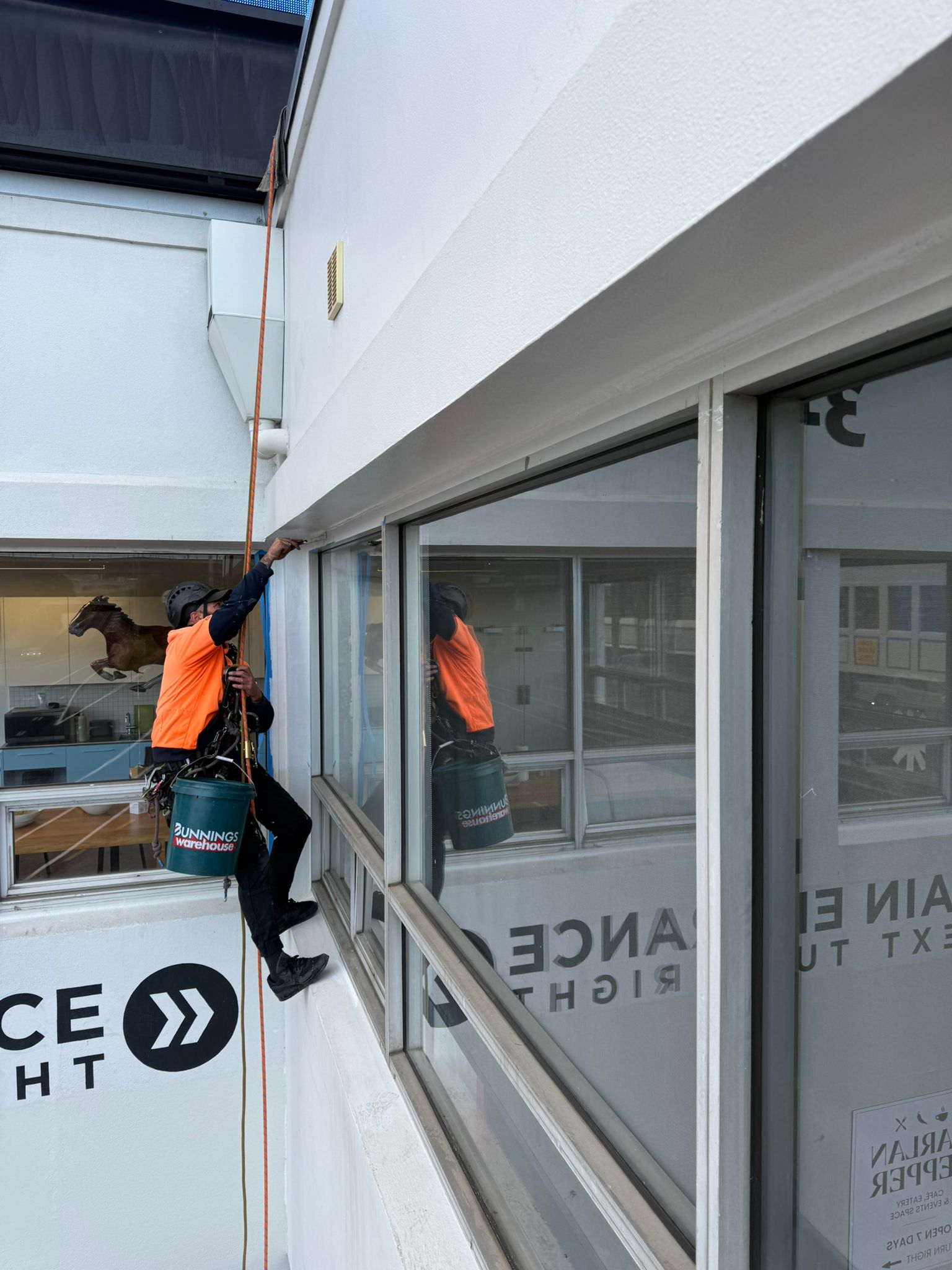 Rope access technician painting an exterior facade