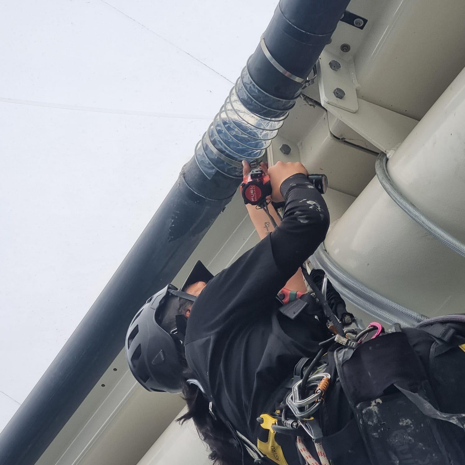 Rope access technician checking equipment while working at height